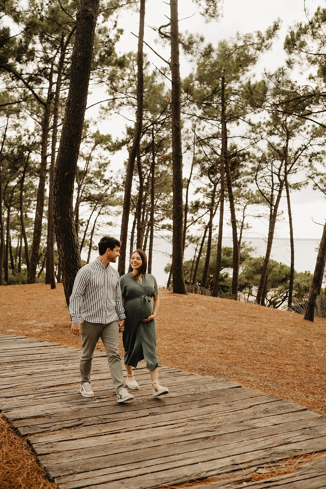 Future maman posant en robe fluide dans la lumière dorée