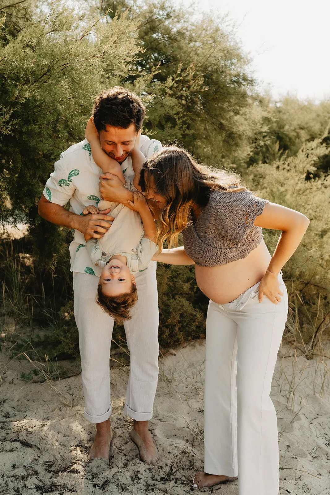 Séance grossesse en famille avec enfant embrassant le ventre de maman