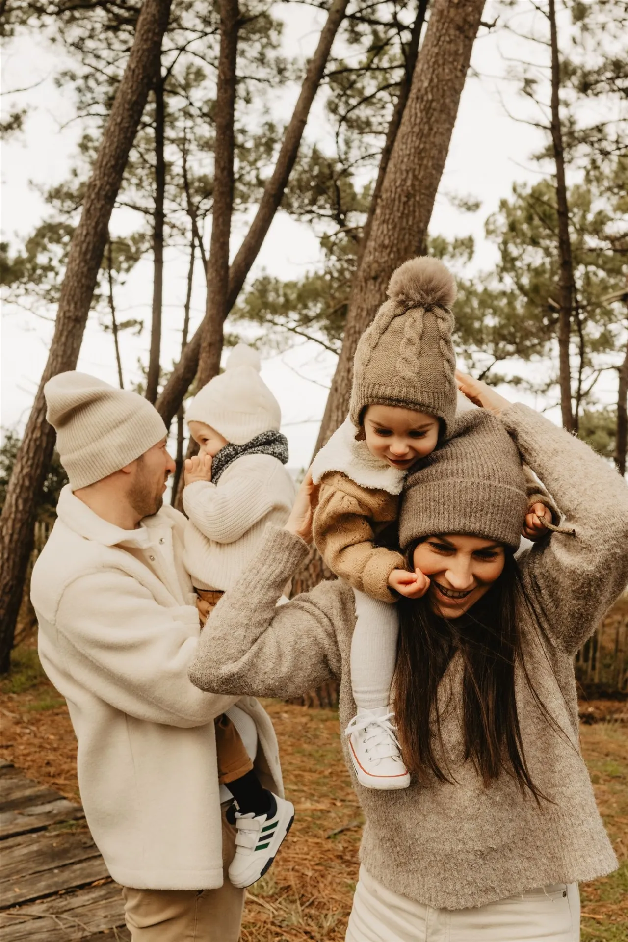 Bébé dans les bras de papa avec maman à côté en forêt